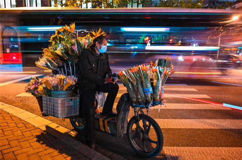 Ein Blumenverkäufer wartet auf einer Straße im Jing’an-Viertel in Schanghai auf Kunden
