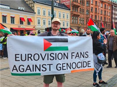 Ein Demonstrant in Malmö hält ein Banner mit der Aufschrift „Eurovision fans against genocide“ hoch
