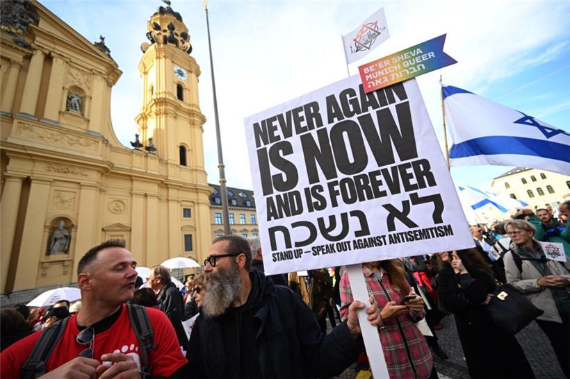 Ein Demonstrant steht in München mit einem Schild mit der Aufschrift „Never agai...