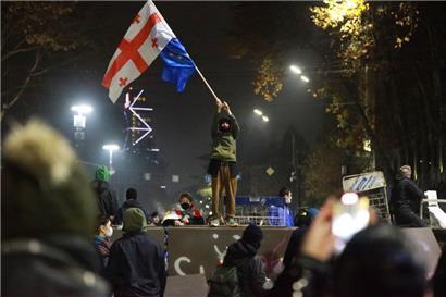Ein Demonstrant steht mit georgischen National- und EU-Flaggen während einer Kundgebung vor dem Parlamentsgebäude, um gegen die Entscheidung der Regierung zu protestieren, die Verhandlungen über den Beitritt zur Europäischen Union für vier Jahre auszusetzen

