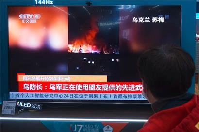 Ein Einwohner sieht sich in einem Einkaufszentrum in Hangzhou in der ostchinesischen Provinz Zhejiang Nachrichten über den Konflikt zwischen Russland und der Ukraine an
