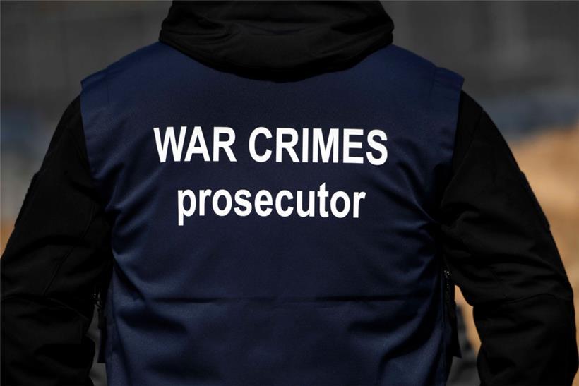 Ein Ermittler eines internationalen Forensik-Teams trägt eine Weste mit der Aufschrift „War Crimes Prosecutor“ („Ankläger für Kriegsverbrechen“)
