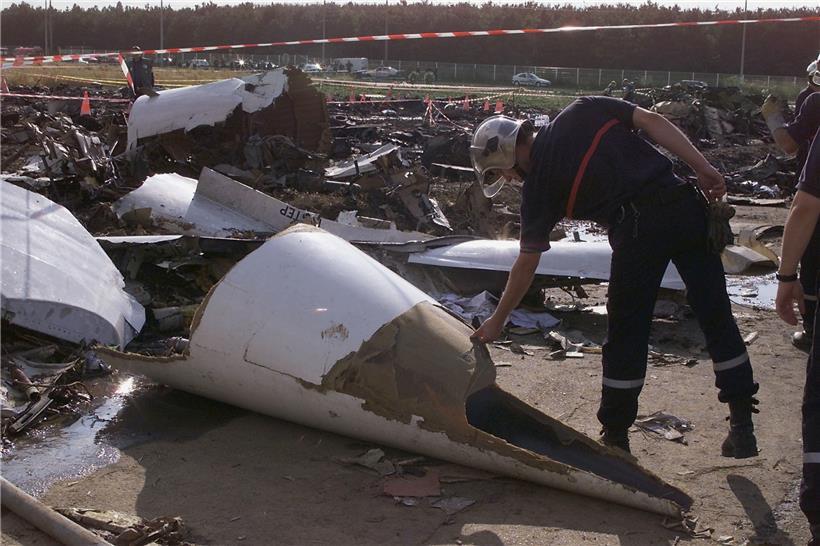 Ein Feuerwehrmann berührt die Nase der Concorde am Absturzort. 
