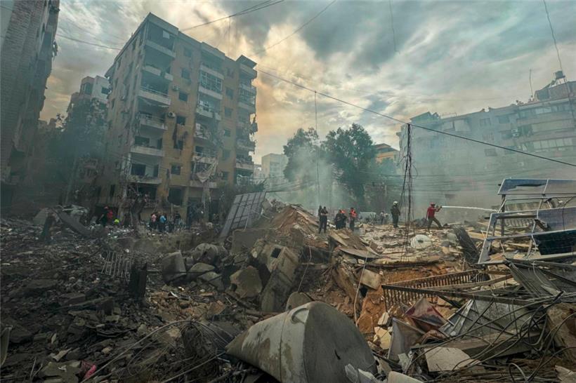Ein Feuerwehrmann (r.) sprüht Wasser auf Trümmer nach einem israelischen Angriff im Süden Beiruts
