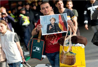 Ein Flüchtling, der kurz zuvor mit einem Zug angekommen ist, läuft Anfang September 2015 auf dem Münchner Hauptbahnhof über den Bahnsteig und hält dabei ein Foto von Angela Merkel in den Händen
