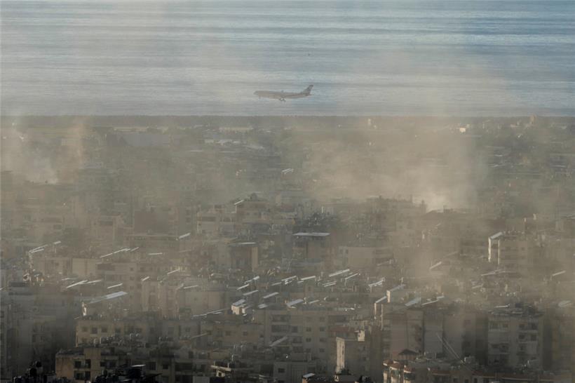 Ein Flugzeug der Middle East Airlines fliegt über den Vorort Dahieh in Beirut, während Rauch von israelischen Luftangriffen aufsteigt
