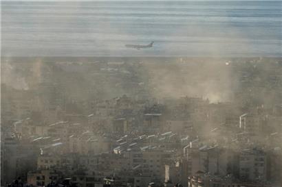 Ein Flugzeug der Middle East Airlines fliegt über den Vorort Dahieh in Beirut, während Rauch von israelischen Luftangriffen aufsteigt
