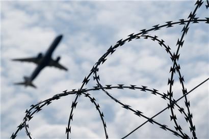 Ein Flugzeug hebt hinter einem Zaun mit Natodraht ab
