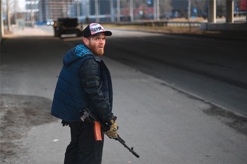 Ein Freiwilliger mit einem Gewehr in der Hand schützt am 25. Februar eine Hauptstraße, die nach Kiew führt
