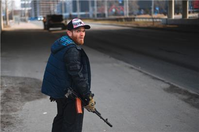 Ein Freiwilliger mit einem Gewehr in der Hand schützt am 25. Februar eine Hauptstraße, die nach Kiew führt
