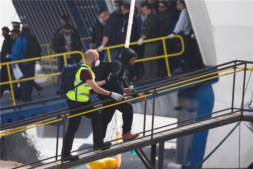 Ein Frontex-Mitarbeiter führt einen Migranten an Bord einer Fähre im Hafen von Mytilini in Griechenland
