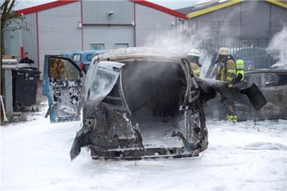 Ein Geldtransporter steht ausgebrannt nach einem Überfall auf einer Straße
