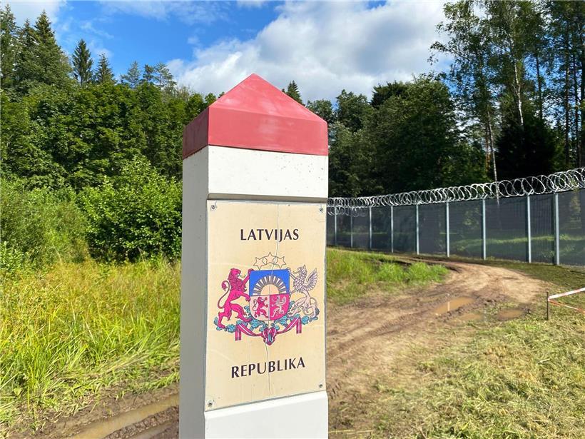 Grenzpfeiler mit Aufschrift „Republik Lettland“ an der lettisch-russischen Grenze in bewaldeter Landschaft