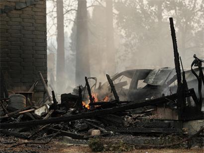 Ein Haus, das durch einen Waldbrand zerstört wurde, schwelt in Spokane