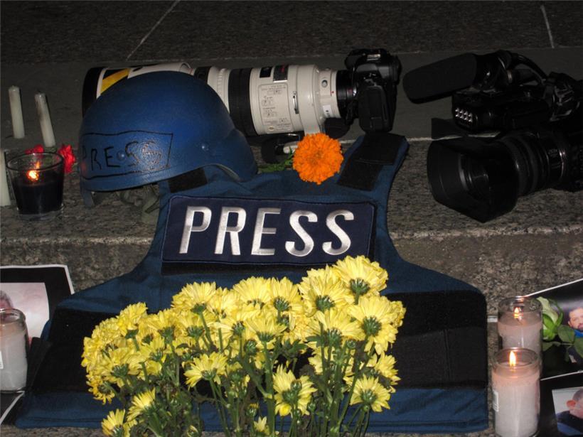 Ein Helm, Kameras und eine Schutzweste – Ausrüstungsgegenstände von Journalisten, die in Kriegsgebieten arbeiten, liegen bei einer Mahnwache neben Blumen und Kerzen auf dem Foley Square
