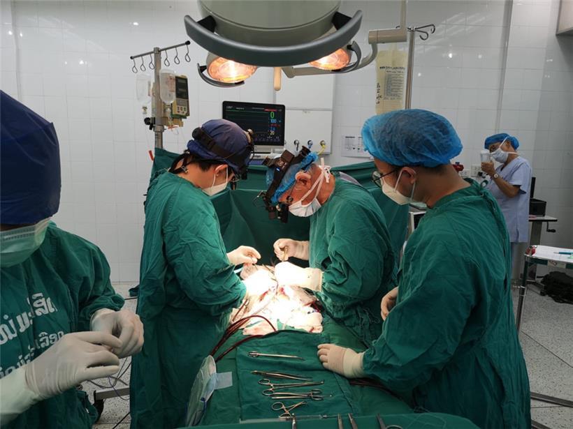 Ein Herzchirurg von ADS wird von laotischen Medizinern während einer Operation assistiert
