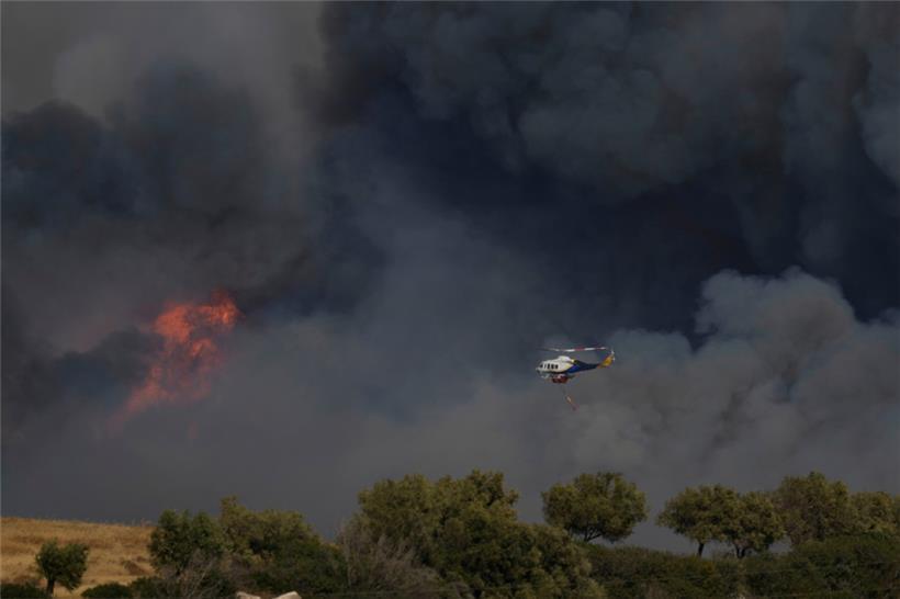 Ein Hubschrauber fliegt durch den Rauch eines Brandes in Keratea, einem Außenbezirk von Athen
