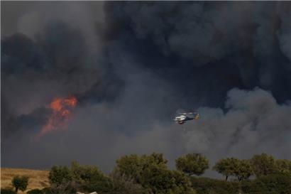 Ein Hubschrauber fliegt durch den Rauch eines Brandes in Keratea, einem Außenbezirk von Athen
