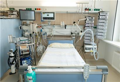 Ein Intensivbett auf einer Intensivstation der Uniklinik Dresden. Links neben dem Bett steht eine Herz-Lungen-Maschine, oben befinden sich die Überwachungsmonitore für die Vitalfunktionen. Rechts neben dem Bett sind ein Beatmungsgerät und Infusionstechnik zu sehen.
