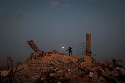 Ein Jugendlicher spielt auf den Trümmern eines zerstörten Gebäudes, während der Vollmond am 4. Dezember 2025 über dem Lager Nuseirat für vertriebene Palästinenser im zentralen Gazastreifen aufgeht.
