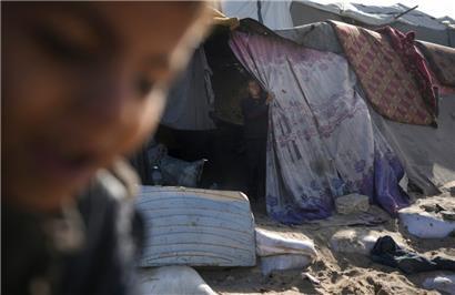 Ein Junge schaut aus einem Zelt, das vor Ort aus Stoff- und Nylonstücken hergestellt wurde, in einem Lager für intern vertriebene Palästinenser am Strand von Deir al-Balah im zentralen Gazastreifen
