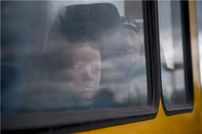 Ein Junge schaut durch das Fenster eines Busses, als Menschen, die vor den Kämpfen in Mariupol fliehen, in einem kleinen Konvoi für Binnenflüchtlinge in Saporischschja ankommen
