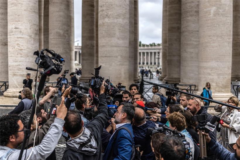 Ein Kardinal wird bei seiner Ankunft vor dem Petersplatz dicht umringt von Journ...