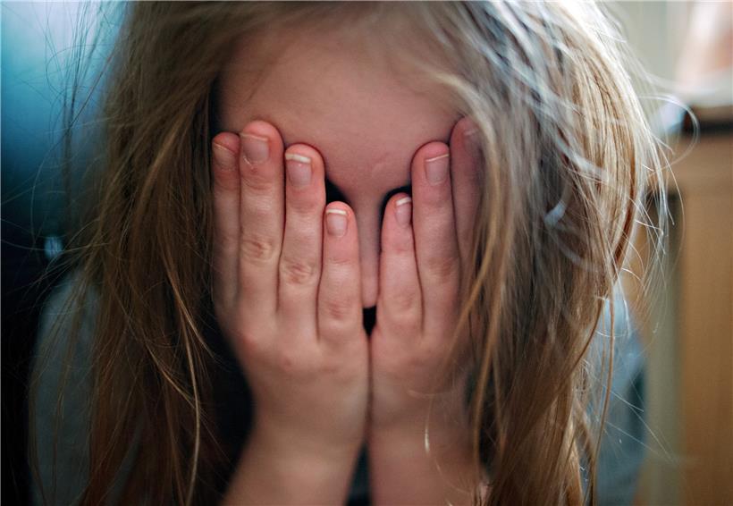 Ein Kind hält sich die Hände an den Kopf. Viele junge Menschen leiden, wenn ein Elternteil oder Geschwister mental erkranken.
