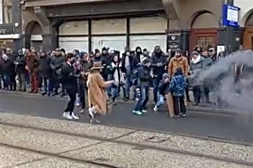 Ein Kind wird zum Foto-Modell – und dazu mit einer Rauchbombe und Plakat ausgestattet. Umstehende Erwachsene machen begeistert Fotos und beklatschen das Geschehen (Screenshot aus Twitter-Video).
