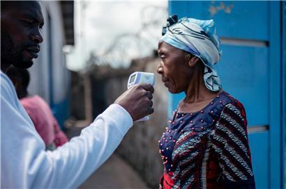 Krankenhausmitarbeiter in Goma misst berührungslos Temperatur einer Besucherin mit Infrarot-Thermometer vor Zutritt