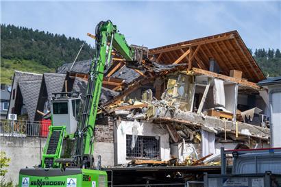 Ein Langbagger beginnt am Giebel des eingestürzten Hotels mit den Abrissarbeiten
