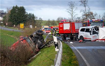 Ein Lastwagen liegt nach einem Frontalzusammenstoß mit einem Kleinbus (r) hinter der Leitplanke an einem Abhang an der Bundesstraße 51 bei Welschbillig
