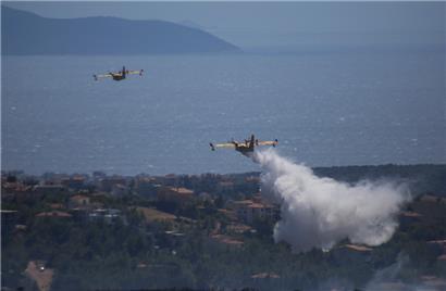 Ein Löschflugzeug wirft im vergangenen Jahr Wasser in der Gegend von Drafi östlich von Athen ab
