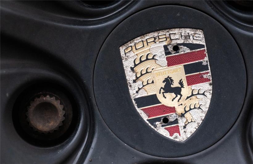Ein Logo der Porsche AG ist an einer älteren Felge eines Porsche-Fahrzeugs zu sehen
