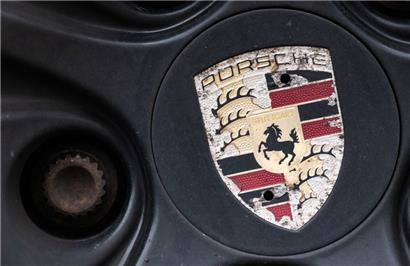 Ein Logo der Porsche AG ist an einer älteren Felge eines Porsche-Fahrzeugs zu sehen
