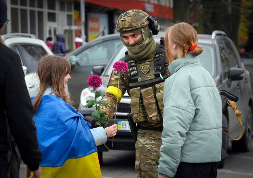 Ein Mädchen, das eine ukrainische Nationalfahne trägt, tauscht mit einem ukrainischen Soldaten Blumen aus. Der Rückzug der Russen aus Cherson war ein Meilenstein in der ukrainischen Gegenwehr gegen den Einmarsch Moskaus vor fast neun Monaten.
