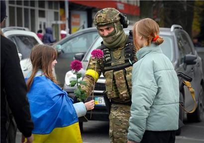Ein Mädchen, das eine ukrainische Nationalfahne trägt, tauscht mit einem ukrainischen Soldaten Blumen aus. Der Rückzug der Russen aus Cherson war ein Meilenstein in der ukrainischen Gegenwehr gegen den Einmarsch Moskaus vor fast neun Monaten.
