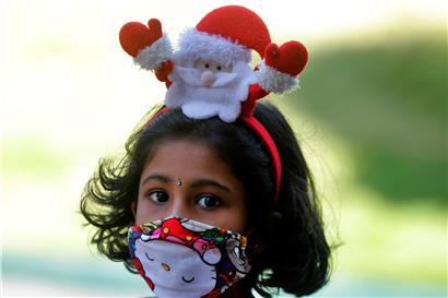 Ein Mädchen trägt einen Weihnachtsmann-Haarreif und eine Maske als Vorsichtsmaßnahme gegen das Coronavirus, als sie für die Weihnachtsmesse in einer Kirche ankommt
