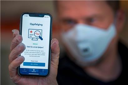 Ein Mann aus Norwegen hält ein Smartphone mit einer Tracing-App hoch. In Luxemburg ist man immer noch unentschieden, ob man die Technik einsetzen soll. 
