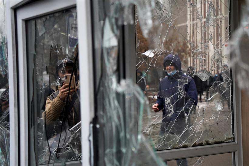 Ein Mann fotografiert die Fenster eines Polizeikiosks, die von Teilnehmern einer Demonstration beschädigt wurden. Aus Protest gegen hohe Energiepreise sind in Kasachstan in Zentralasien den dritten Tag in Folge Tausende Menschen auf die Straße gegangen. 
