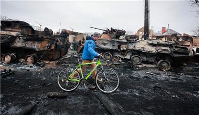 Ein Mann geht an den Überresten eines russischen Militärfahrzeugs in Bucha, nahe der ukrainischen Hauptstadt Kiew, vorbei
