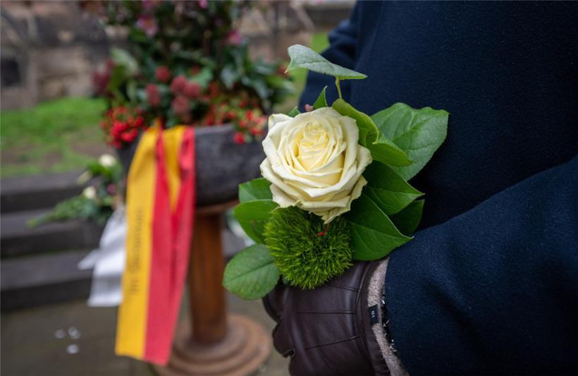 Ein Mann hält eine weiße Rose vor der Porta Nigra zum Gedenken an die Opfer und ...