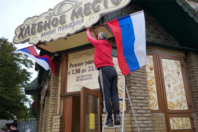 Ein Mann hängt am Dienstag eine russische Fahne an einem Café im ukrainischen Luhansk auf
