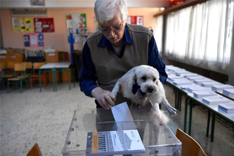 Ein Mann mit seinem Hund gibt seine Stimme in einem Wahllokal im Rahmen der Parlamentswahlen ab.
