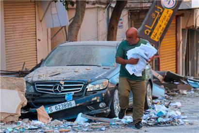 Ein Mann sammelt in der südlibanesischen Stadt Tyre Papiere ein, nachdem ein Finanzinstitut von einem israelischen Angriff getroffen wurde
