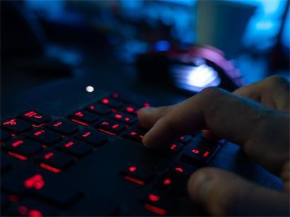 Ein Mann sitzt am Rechner und tippt auf einer Tastatur