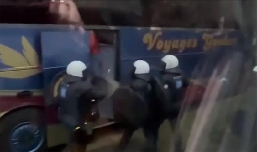 Ein Mann tritt beim Betreten des Busses die Polizisten, nachdem diese die Menschen aufgefordert haben, in den Bus zu steigen.
