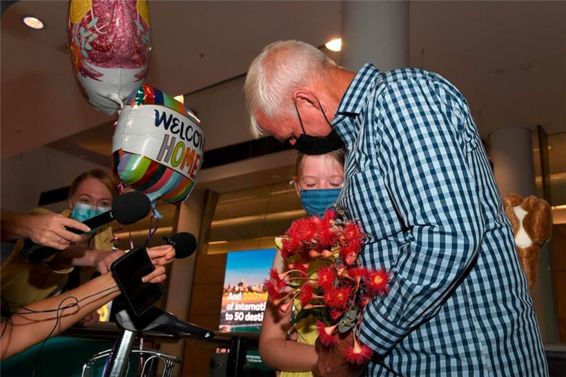 Ein Mann umarmt in Sydney nach langer Trennung seine Enkelin
