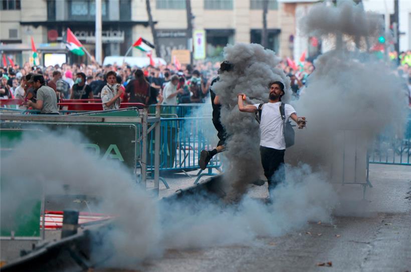 Ein Mann wirft eine Rauchfackel, nachdem pro-palästinensische Demonstranten während der 21. und letzten Etappe in Madrid auf die Straße gestürmt sind
