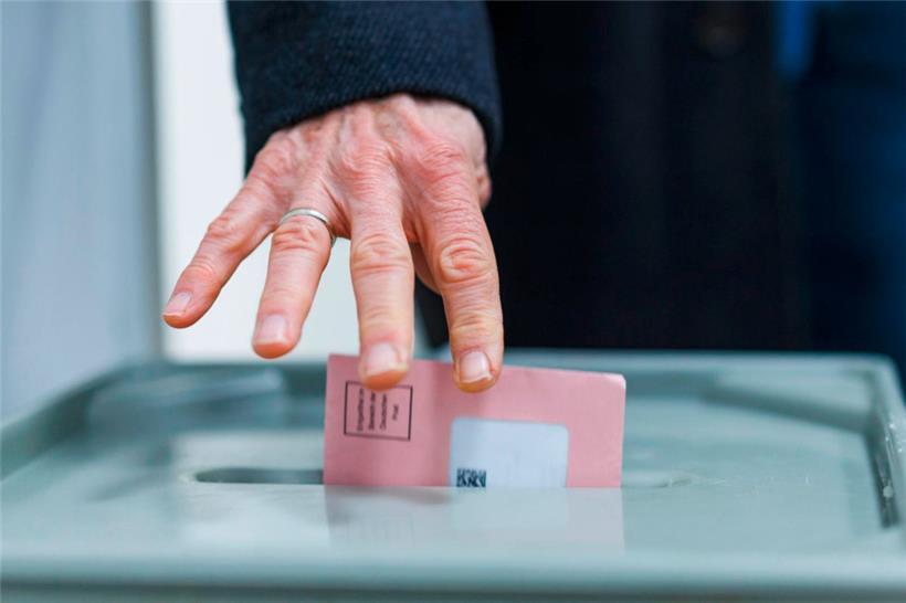 Ein Mann wirft seine Wahlunterlagen in eine Wahlurne
